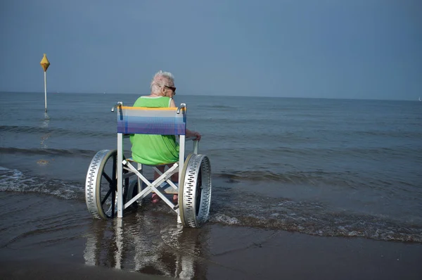 Пожилая женщина в инвалидной коляске в море — стоковое фото