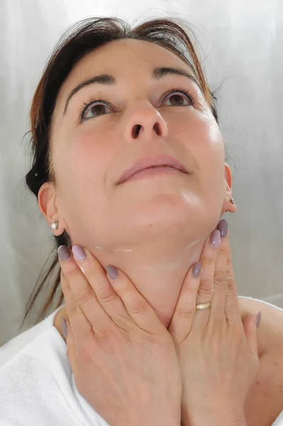 Mujer madura pone crema en la cara — Foto de Stock