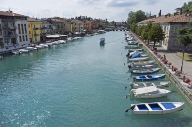 10 Temmuz, 2019 - Peschiera del Garda, İtalya: Güzel tarihi şehir merkezi. Rengarenk çiçekler, binalar ve teknelerle su kanalı boyunca gezinti ve eğlence
