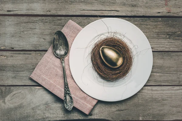 Ovo de Páscoa dourado no prato — Fotografia de Stock