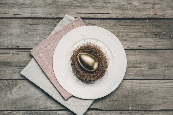 Золотое пасхальное яйцо на тарелке
 