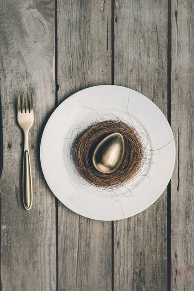 Zlaté velikonoční vajíčko na desce — Stock fotografie