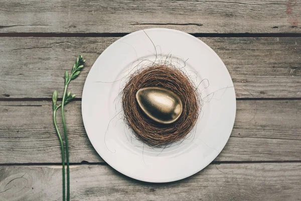Золотое пасхальное яйцо на тарелке — стоковое фото