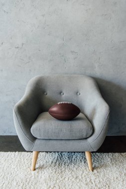 american football ball on grey armchair clipart