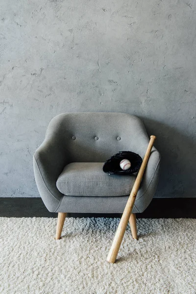 Baseball bat and ball with glove on armchair — Stock Photo, Image