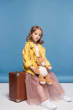 Girl with suitcase and teddy bear 