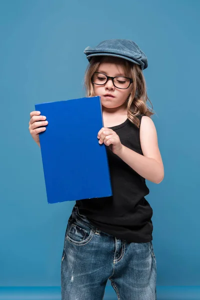 Menina criança em óculos segurando livro — Fotografia de Stock