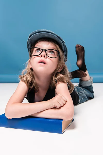 Kid girl leaning on book and looking up — Stock Photo, Image
