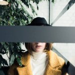Femme en chapeau près des feuilles vertes