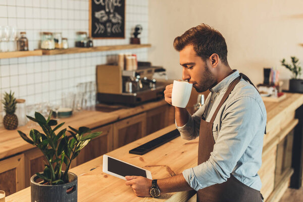 barista with cup of coffee using tablet