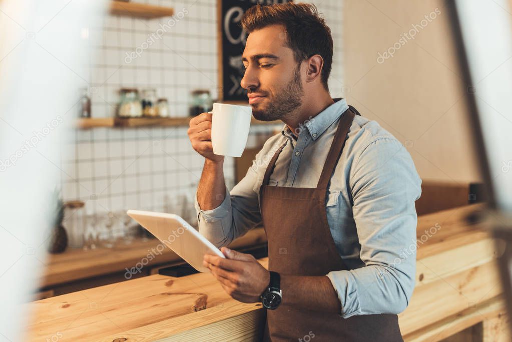 barista with cup of coffee using tablet