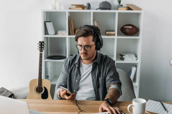 Hombre en auriculares usando teléfono inteligente — Foto de Stock