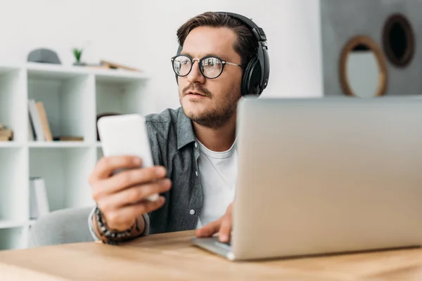 Hombre en auriculares usando teléfono inteligente — Foto de Stock