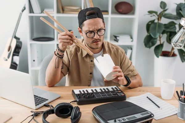 Musiker isst chinesisches Essen mit Trommelstöcken — Stockfoto