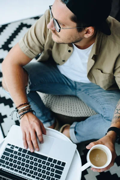 Человек с чашкой кофе с помощью ноутбука — стоковое фото