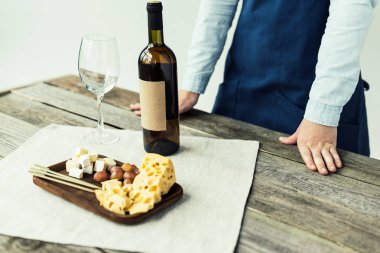 Sommelier ayakta masada şarap şişesi ile