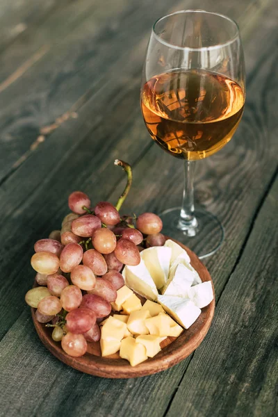 Бокал вина и тарелки с виноградом и сыром — стоковое фото