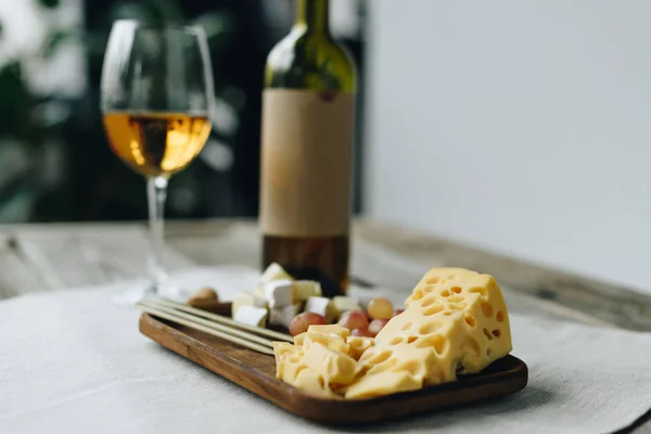 Glass with wine and plate with cheese and grapes — Stock Photo, Image