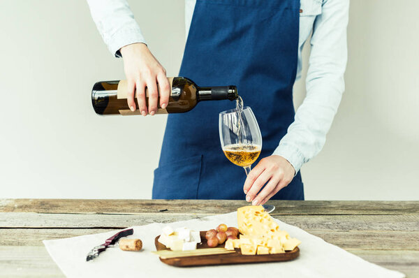 sommelier pouring white wine into glass 