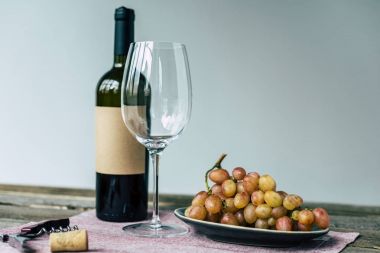 Wine bottle with empty glass and grapes  clipart