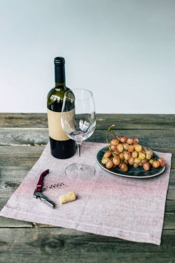 Wine bottle with empty glass and grapes clipart