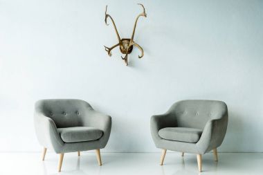gray armchairs and antlers on wall clipart