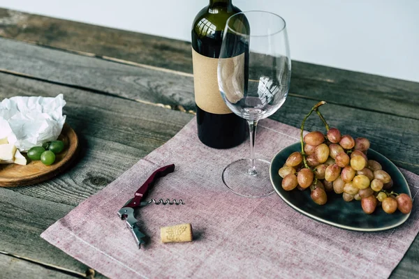 Botella de vino con vaso vacío y uvas —  Fotos de Stock