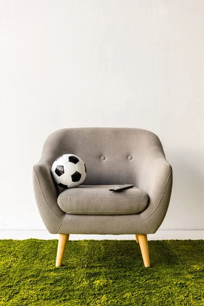 足球球和远程控制器在扶手椅上 — 图库照片
