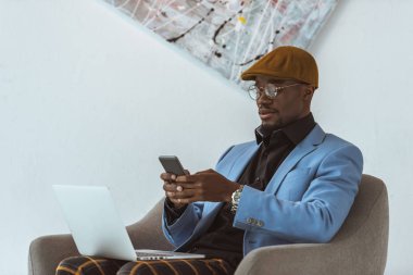 dizüstü bilgisayar ve akıllı telefon kullanan Afrikalı-Amerikalı adam