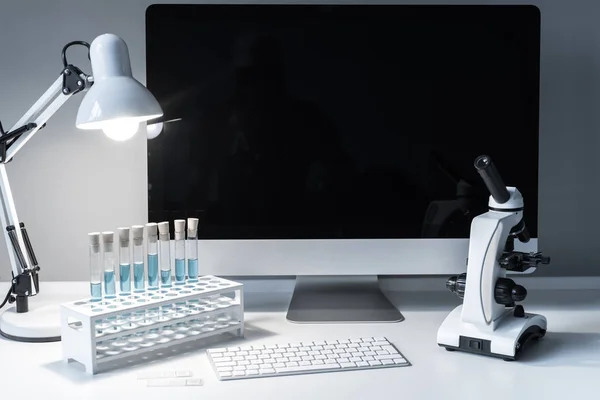 microscope and test tubes with liquid on working table