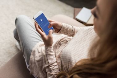 kadın kanepede ile facebook app üstünde perde smartphone kullanarak kırpılmış atış