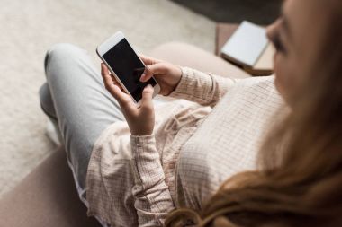 genç kadının evde kanepede smartphone kullanarak yüksek açılı görünüş