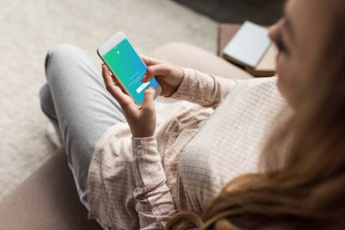 kadın kanepede ile heyecan app üstünde perde smartphone kullanarak kırpılmış atış