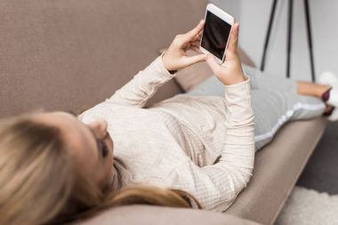 genç kadın evde kanepede dinlenirken Smartphone kullanarak