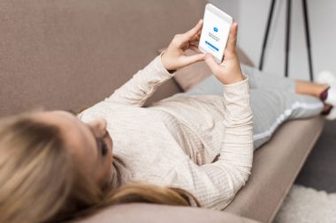 woman on couch using smartphone with messenger app on screen