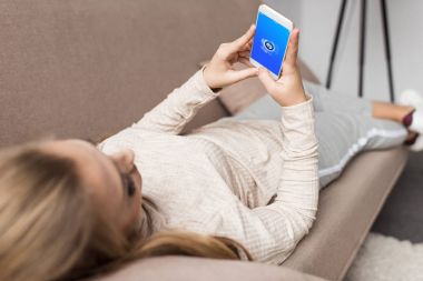 kadın kanepede shazam app üstünde perde smartphone kullanarak