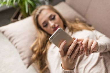 genç kadının evde kanepede smartphone kullanarak yakın çekim shot