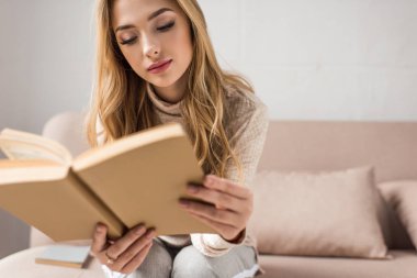 çekici genç kadın evde rahat kanepede kitap okuma