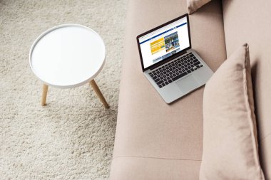 high angle view of laptop standing on cozy couch with booking website on screen