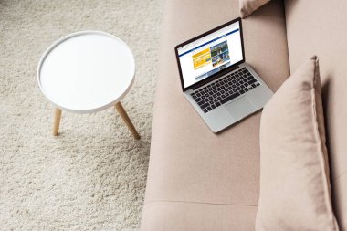 high angle view of laptop standing on cozy couch with booking website on screen clipart