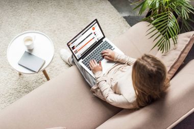 yüksek açılı görünüş kadının evde kanepede oturan ve dizüstü bilgisayar ekranında soundcloud Web sitesi ile kullanma