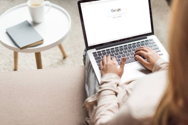 kırpılan kadın evde kanepede oturan ve google Web sitesinde ekran ile dizüstü bilgisayar kullanarak