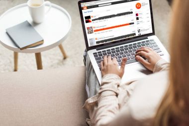 kırpılan kadın evde kanepede oturan ve dizüstü bilgisayar ekranında soundcloud Web sitesi ile kullanma