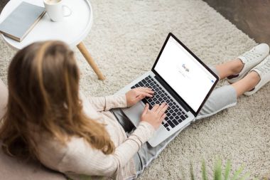kadının evde yüksek açılı görünüş katta oturan ve google Web sitesinde ekran ile dizüstü bilgisayar kullanarak