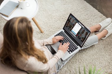 kadının evde yüksek açılı görünüş katta oturan ve LinkedIn Web sitesinde ekran ile dizüstü bilgisayar kullanarak