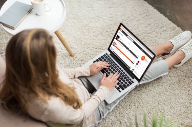 kadının evde yüksek açılı görünüş katta oturan ve dizüstü bilgisayar ekranında soundcloud Web sitesi ile kullanma