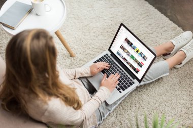 kadının evde yüksek açılı görünüş katta oturan ve youtube Web sitesinde ekran ile dizüstü bilgisayar kullanarak