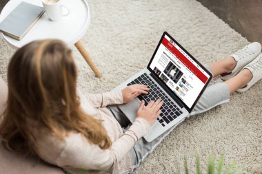 kadının evde yüksek açılı görünüş katta oturan ve bbc Web sitesinde ekran ile dizüstü bilgisayar kullanarak