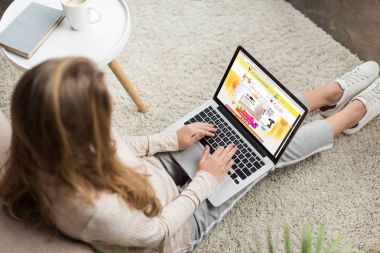 kadının evde yüksek açılı görünüş katta oturan ve aliexpress Web sitesinde ekran ile dizüstü bilgisayar kullanarak