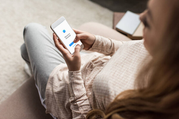 cropped shot of woman on couch using smartphone with messenger app on screen